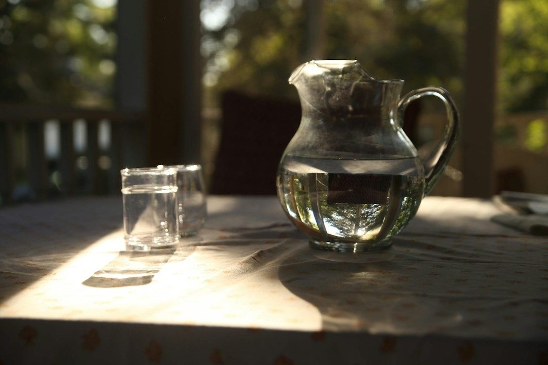 Glaskanna och dricksglas med vatten i varmt morgonljus